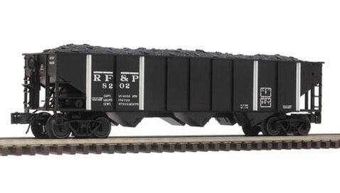Photo of an O gauge model of a black open top three bay hopper car with four white vertical stripes lettered for RF&P sitting on a piece of track on white background.